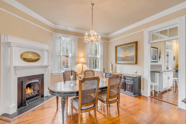 dining room featuring light wood-type flooring, a notable chandelier, and ornamental molding