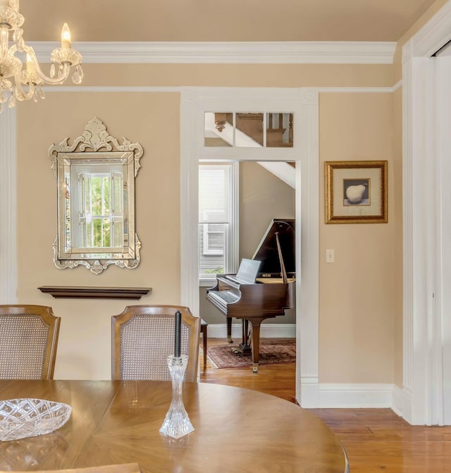 dining space with a notable chandelier, wood-type flooring, and ornamental molding