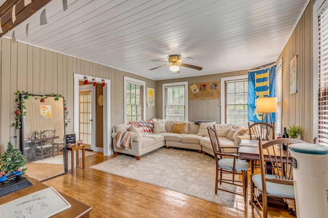 living room with ceiling fan, hardwood / wood-style floors, and wooden walls