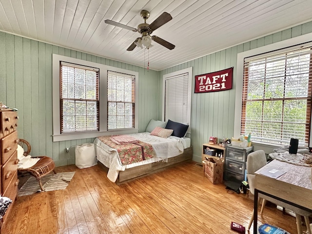 bedroom with ceiling fan, wood walls, light wood-type flooring, and wood ceiling