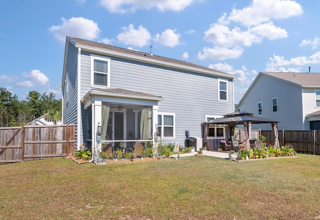 rear view of house with a lawn, a sunroom, and a gazebo