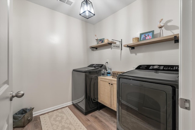 laundry area with cabinets, washer and dryer, and light wood-type flooring