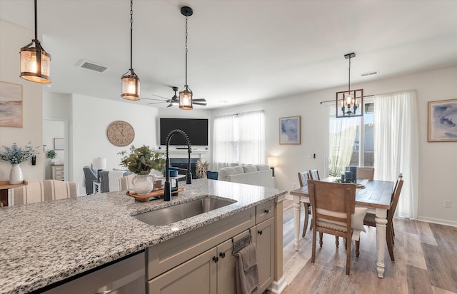 kitchen featuring light hardwood / wood-style floors, sink, pendant lighting, and light stone counters