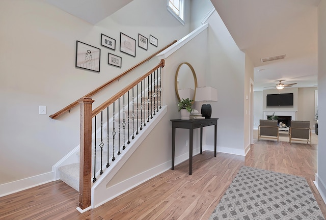 staircase featuring ceiling fan and hardwood / wood-style floors