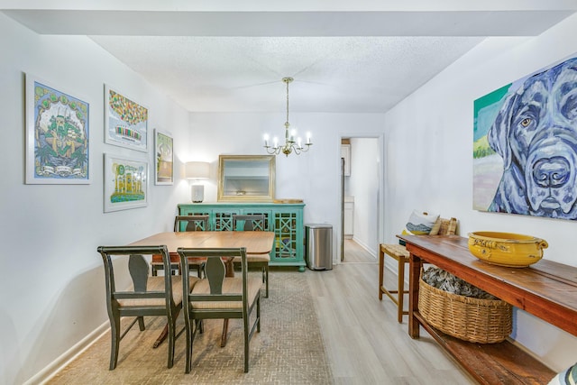 dining area featuring light hardwood / wood-style floors, a textured ceiling, and a notable chandelier