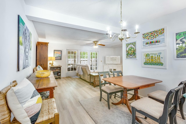 dining space with ceiling fan with notable chandelier and light hardwood / wood-style floors