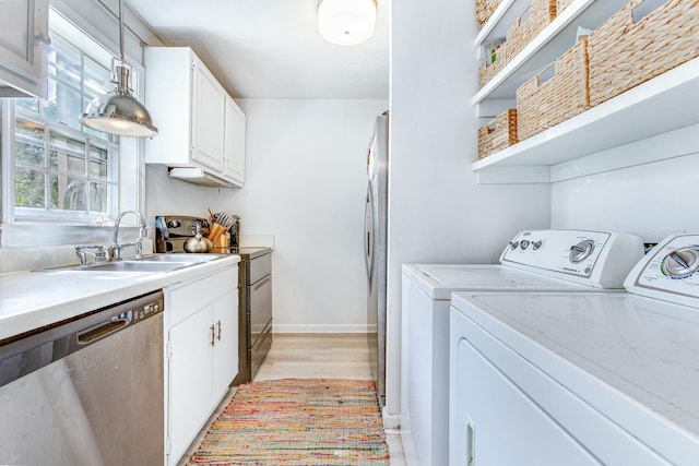 laundry area with separate washer and dryer, sink, and light hardwood / wood-style flooring