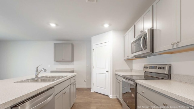 kitchen featuring gray cabinets, sink, appliances with stainless steel finishes, and light hardwood / wood-style flooring