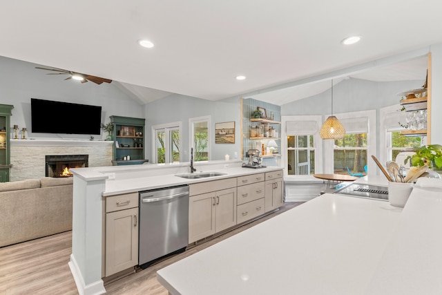 kitchen featuring dishwasher, sink, hanging light fixtures, lofted ceiling, and a fireplace