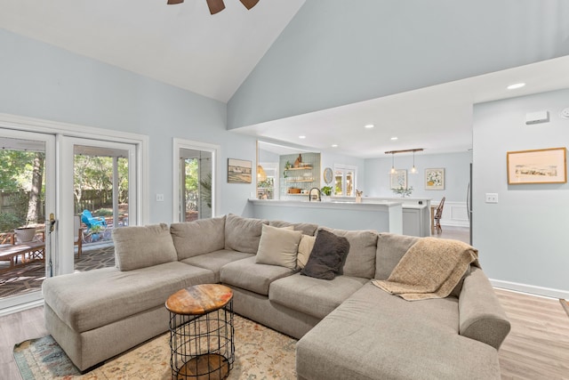 living room with ceiling fan, light hardwood / wood-style flooring, and high vaulted ceiling