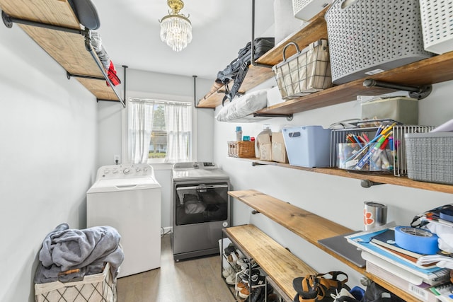 laundry area with washer and clothes dryer, wood-type flooring, and an inviting chandelier