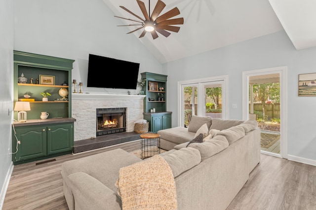 living room featuring ceiling fan, a fireplace, high vaulted ceiling, and light hardwood / wood-style floors