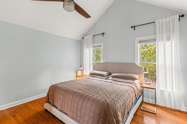 bedroom featuring multiple windows, wood-type flooring, high vaulted ceiling, and ceiling fan