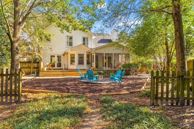 back of house featuring a wooden deck, a sunroom, and an outdoor fire pit