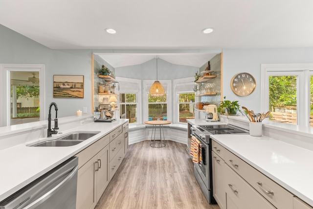 kitchen featuring stainless steel appliances, vaulted ceiling, sink, pendant lighting, and light hardwood / wood-style floors