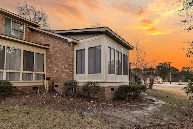 view of side of home featuring a sunroom, crawl space, and brick siding