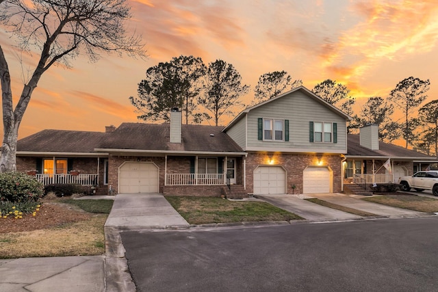 view of front of property with a porch, concrete driveway, and brick siding