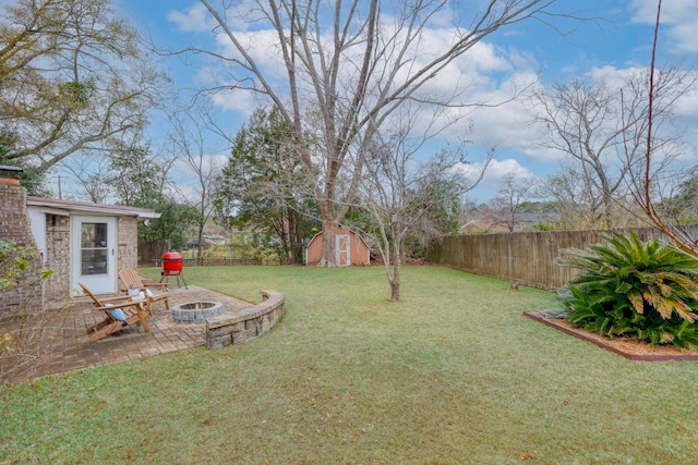 view of yard featuring an outdoor fire pit, a storage shed, and a patio