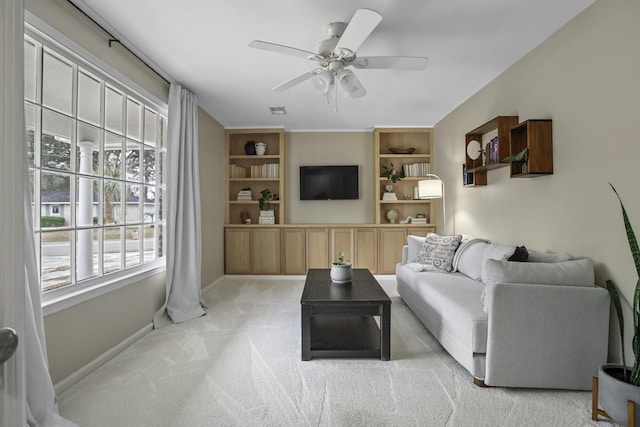 living room with ceiling fan, built in shelves, and light carpet