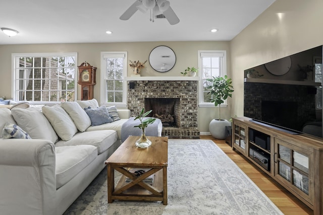 living room featuring ceiling fan, hardwood / wood-style floors, and a fireplace