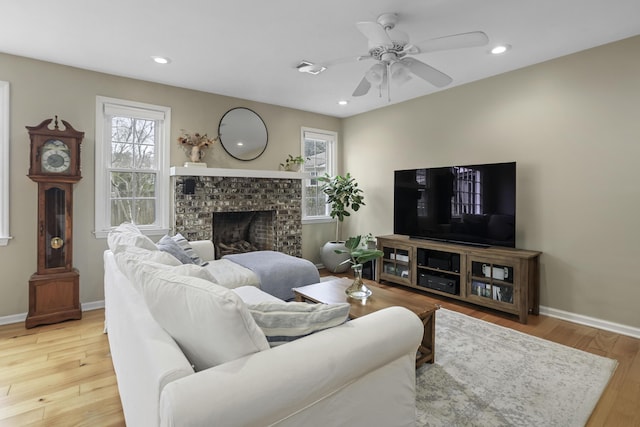 living room featuring hardwood / wood-style flooring, ceiling fan, and a fireplace