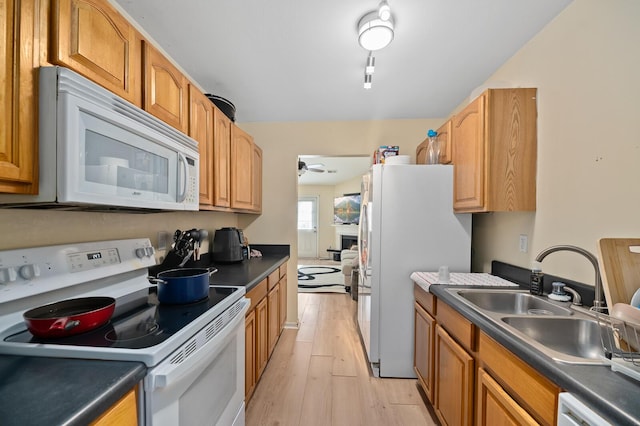 kitchen featuring ceiling fan, white appliances, sink, and light wood-type flooring