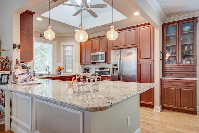kitchen featuring ornamental molding, light stone countertops, stainless steel appliances, and light wood finished floors
