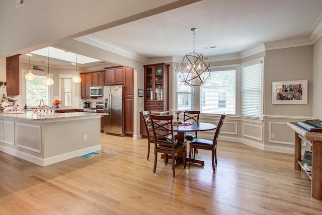 dining area with an inviting chandelier, ornamental molding, light wood-style floors, and a wealth of natural light