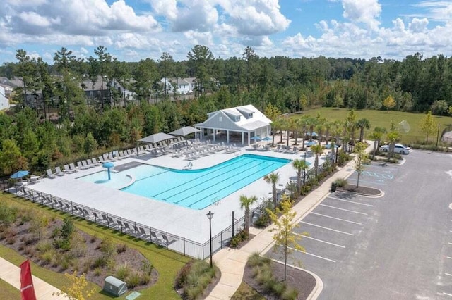 pool with a patio area, fence, and a view of trees