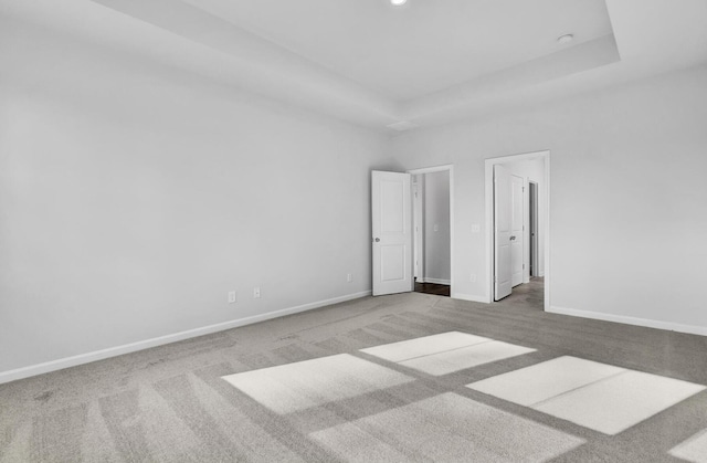 carpeted spare room with baseboards, a raised ceiling, and recessed lighting