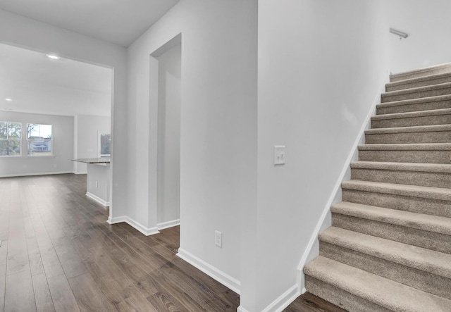 stairway with wood finished floors and baseboards