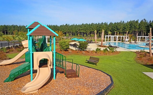 communal playground featuring a community pool, a lawn, and a forest view