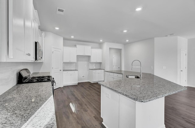 kitchen with stainless steel appliances, a sink, dark wood finished floors, a large island, and decorative backsplash