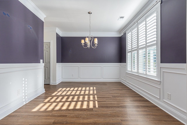 unfurnished dining area with a chandelier, ornamental molding, and dark wood-type flooring