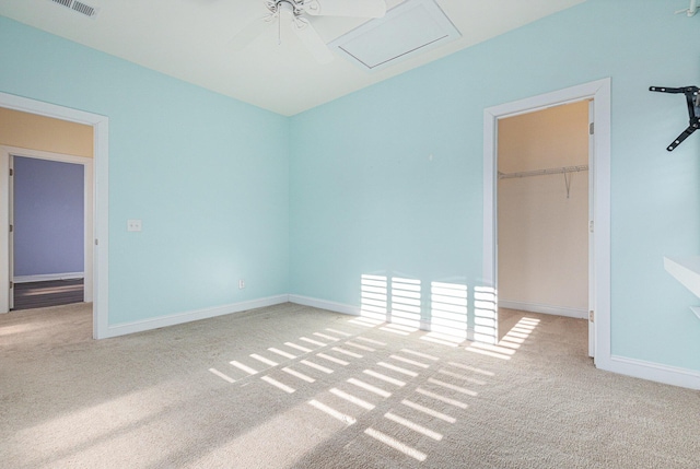 unfurnished bedroom with ceiling fan, a closet, a walk in closet, and carpet floors