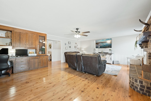 living room with built in desk, light hardwood / wood-style flooring, ceiling fan, and crown molding