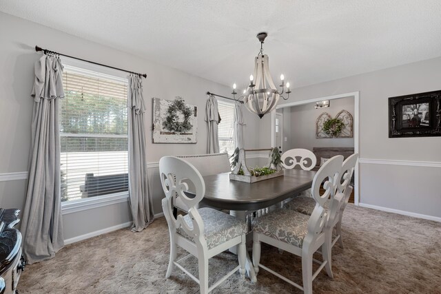 carpeted dining room with a chandelier and a textured ceiling