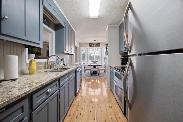 kitchen featuring pendant lighting, sink, a notable chandelier, light hardwood / wood-style floors, and stainless steel appliances