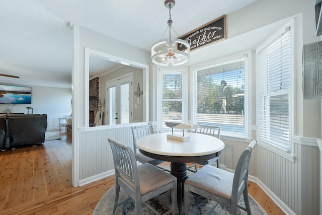 dining area with hardwood / wood-style floors, french doors, crown molding, and an inviting chandelier