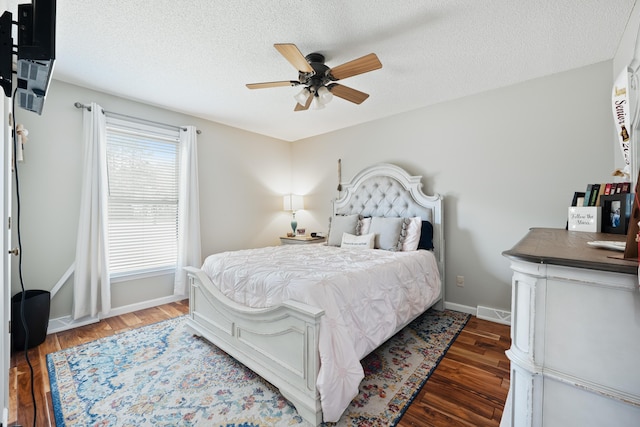 bedroom with a textured ceiling, ceiling fan, and dark wood-type flooring