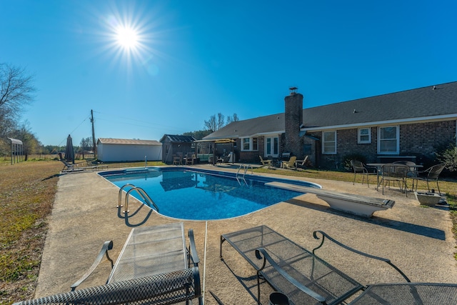 view of swimming pool with a patio and a diving board