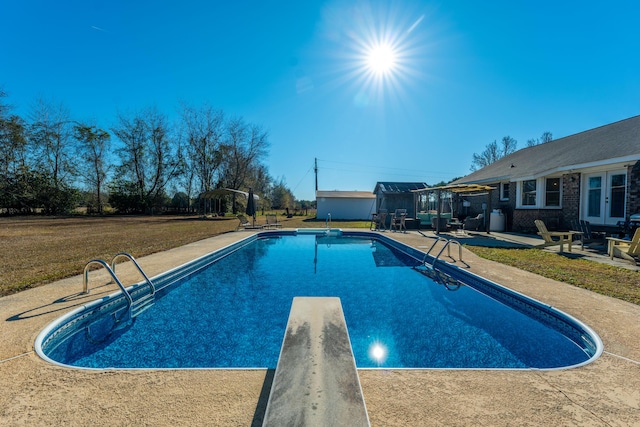 view of swimming pool featuring french doors, a patio, a diving board, and a yard