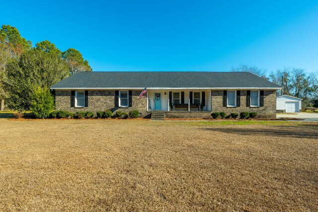 ranch-style home featuring a garage, covered porch, an outdoor structure, and a front yard