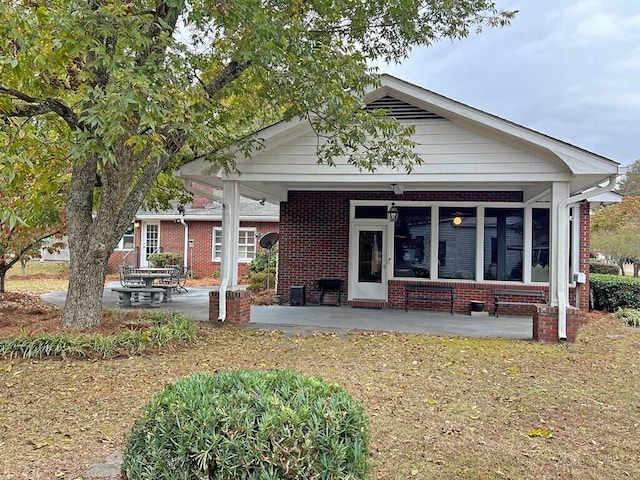 back of house with a yard, a patio, and a sunroom