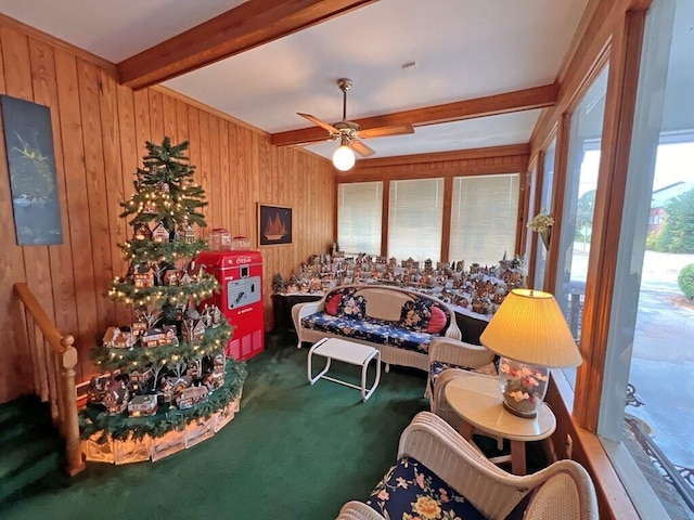 carpeted living room with beamed ceiling, ceiling fan, and wooden walls