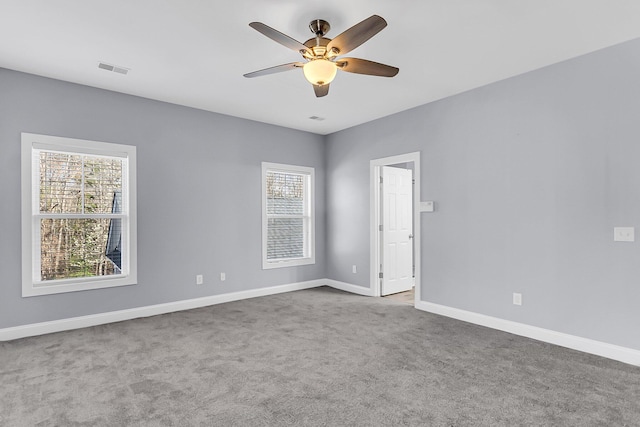 carpeted empty room with visible vents, baseboards, and a ceiling fan