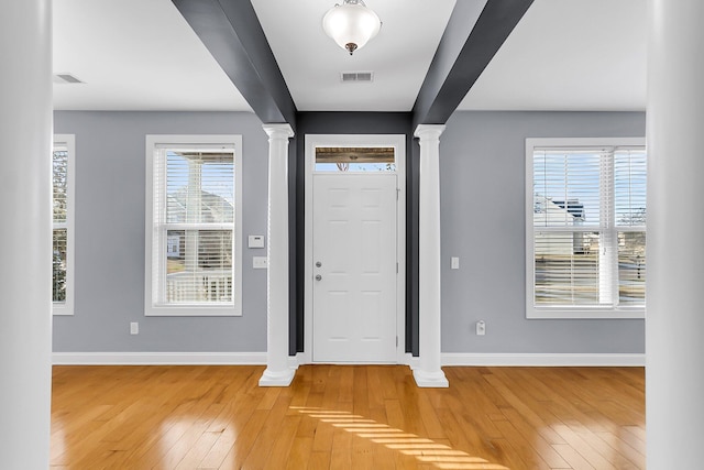 entrance foyer featuring decorative columns, baseboards, light wood-style floors, and visible vents