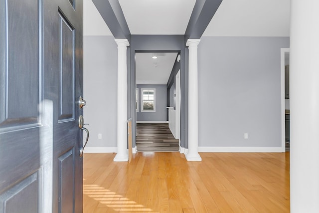 foyer featuring light wood-type flooring, baseboards, and ornate columns