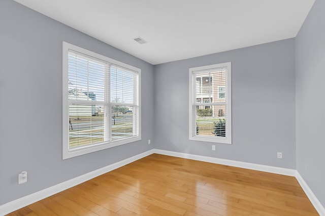 empty room featuring light wood finished floors, visible vents, and baseboards