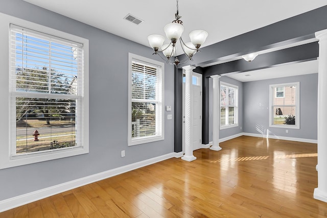 unfurnished dining area with visible vents, ornate columns, and hardwood / wood-style flooring